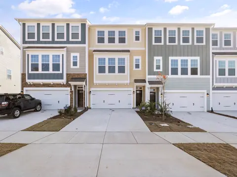 Row of three-story townhomes with garages and short driveways