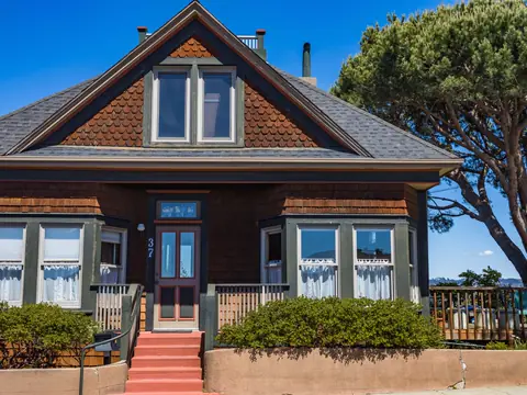 Brown shingle house with bay windows and red front steps