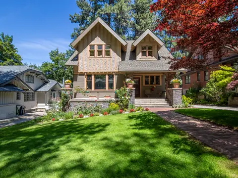 Two-story Victorian house with a wide green lawn and mature trees