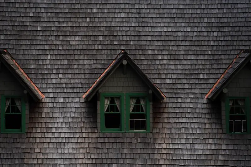 Three dormers with green windows on a cedar shingle roof