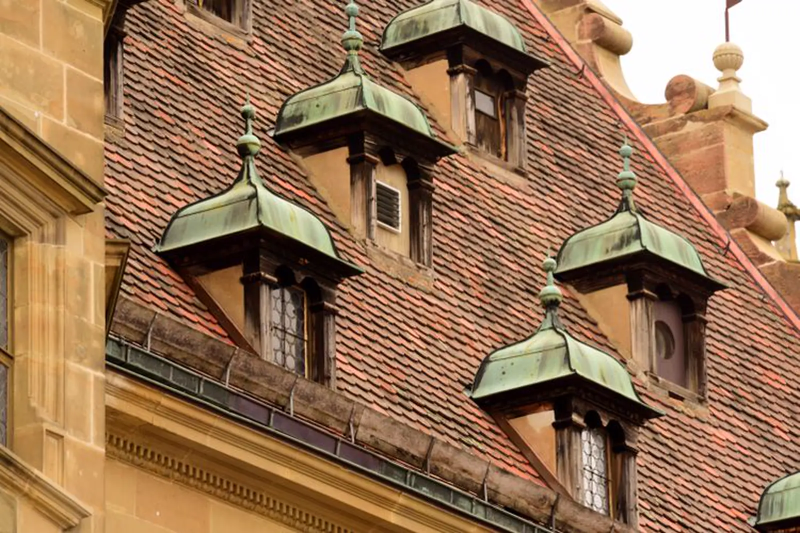 Row of dormers capped in green-patinated copper on a tiled roof