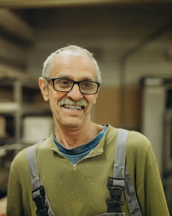 Walt Hagen, smiling in glasses and work overalls in the shop