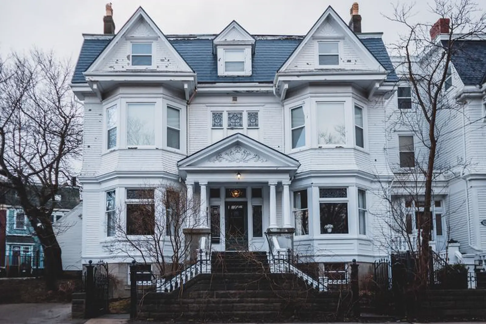 White Queen Anne house with a gray slate roof and three dormers