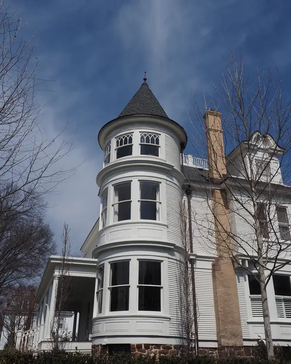 White Victorian house with a round turret and a dark slate cap