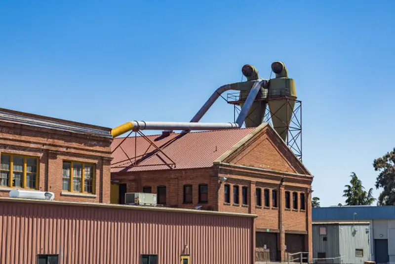 Red brick factory building with large ducts and dust collectors on the roof