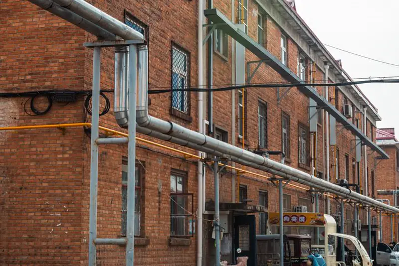 Three-story brick school building with exterior pipes and a flat roof line