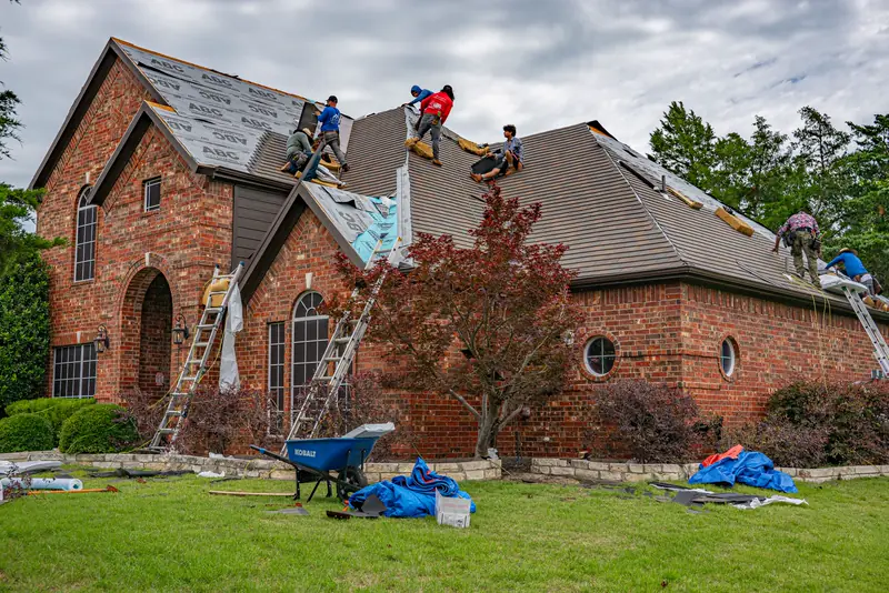 Roofers working across the slopes of a large brick home
