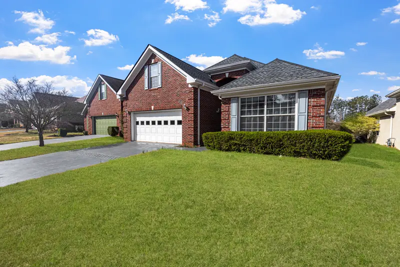 Red brick home with a new roof and a green front lawn