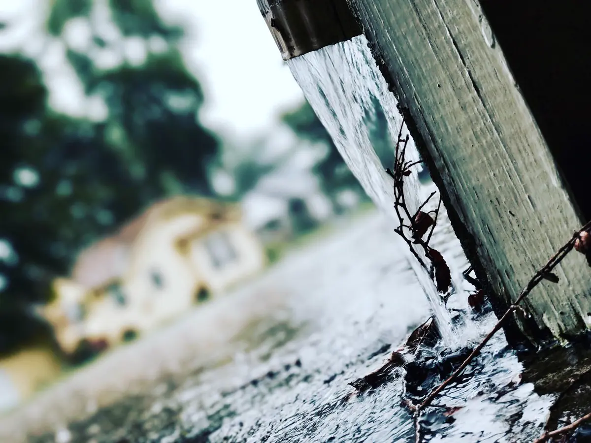 Rainwater pouring from a downspout during a storm