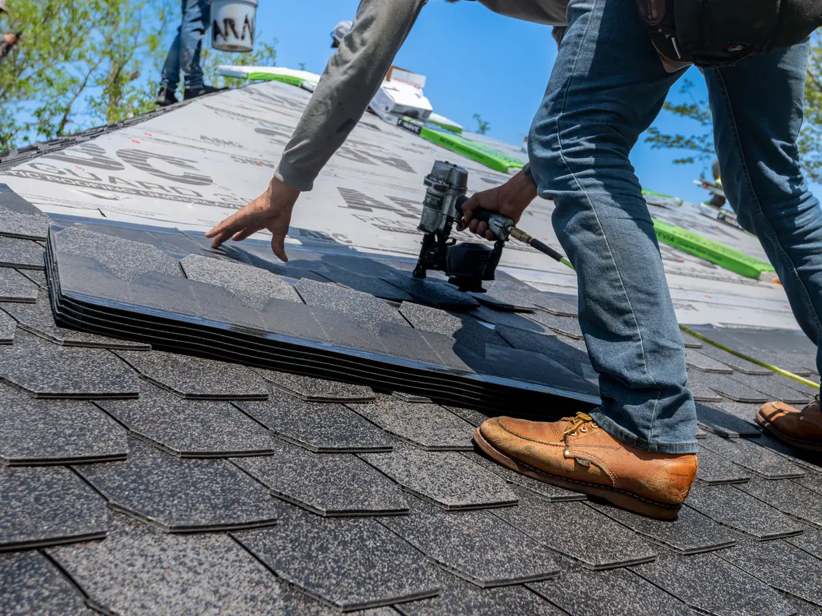 Roofer fastening a new architectural shingle with a nail gun
