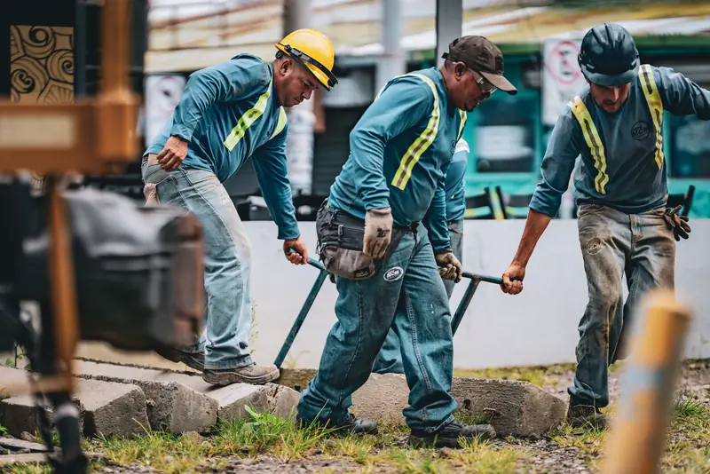 A construction crew in hard hats and safety vests works on a job site