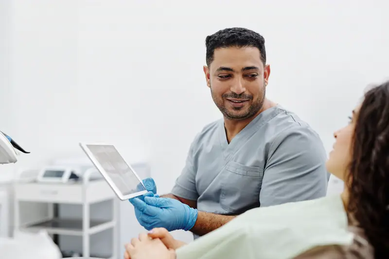 A Corridor provider in scrubs reviews results on a tablet with a patient