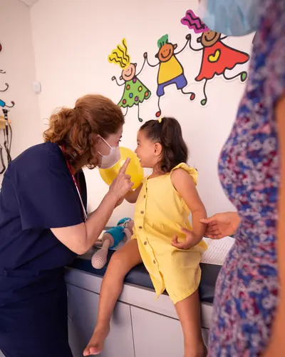 Nurse Ana Morales chats with a little girl on the exam table