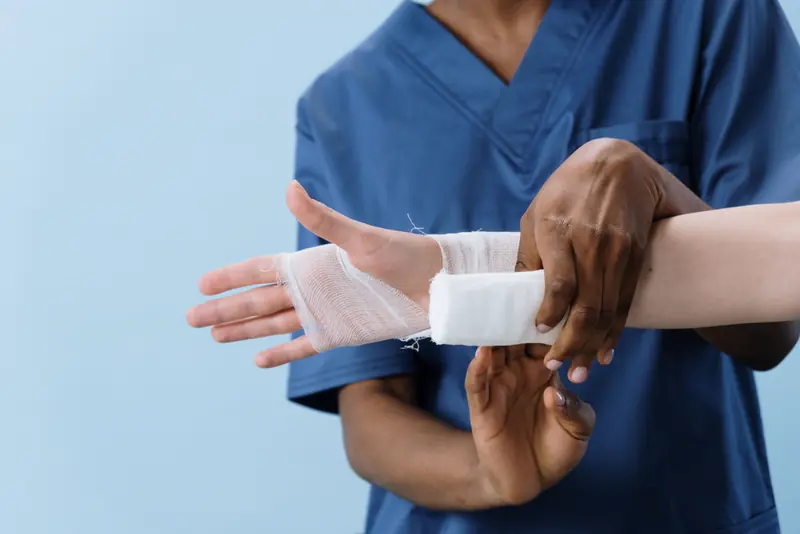 A provider wraps a bandage around a patient's injured hand