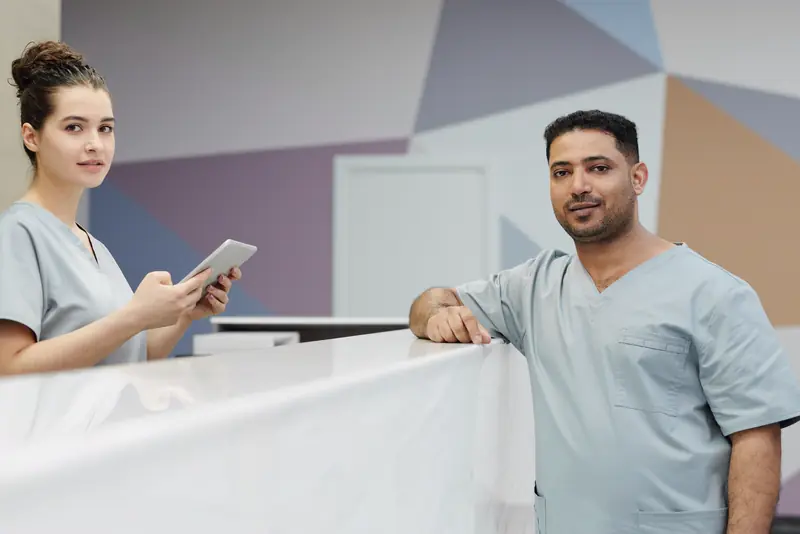 Two NorthStar staff members smiling behind the front desk of a bright clinic