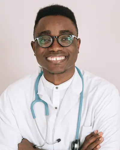 Kwame Asante smiling in a white coat with a stethoscope