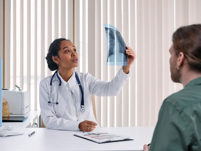 A NorthStar physician holds up a chest x-ray and explains it to a patient